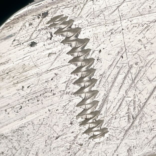 Close-up of a zig-zag line scratched on the lid.