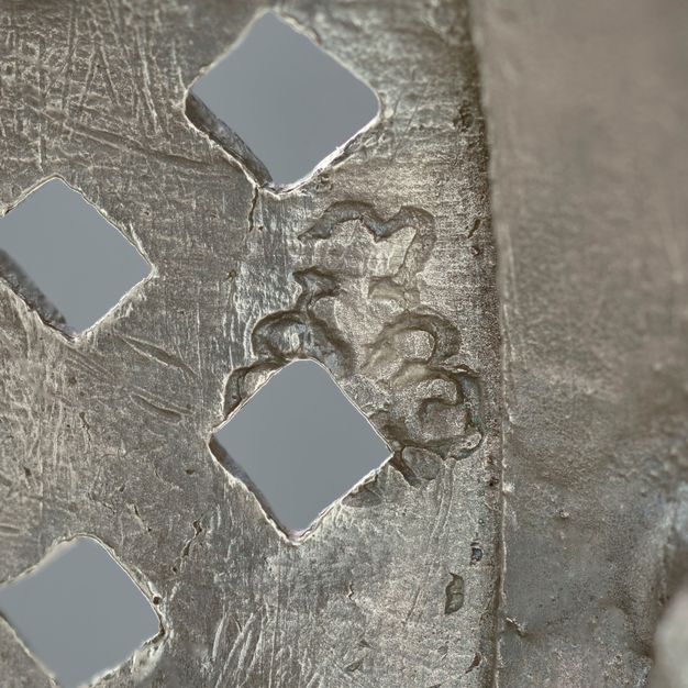 Close-up of the letters S and G stamped on the lid behind four square attachments.