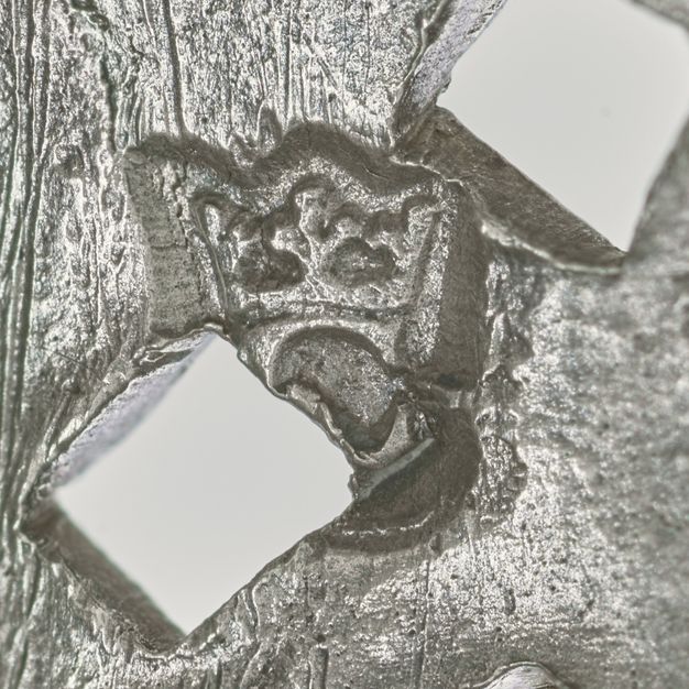 Close-up of a crowned C behind two squares stamped on the lid.