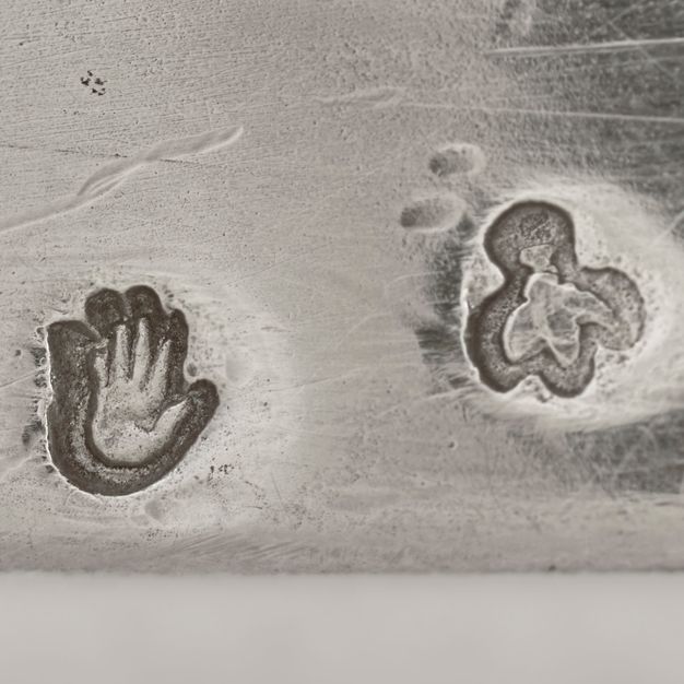 Close-up of a hand and a fly stamped on the vessel.