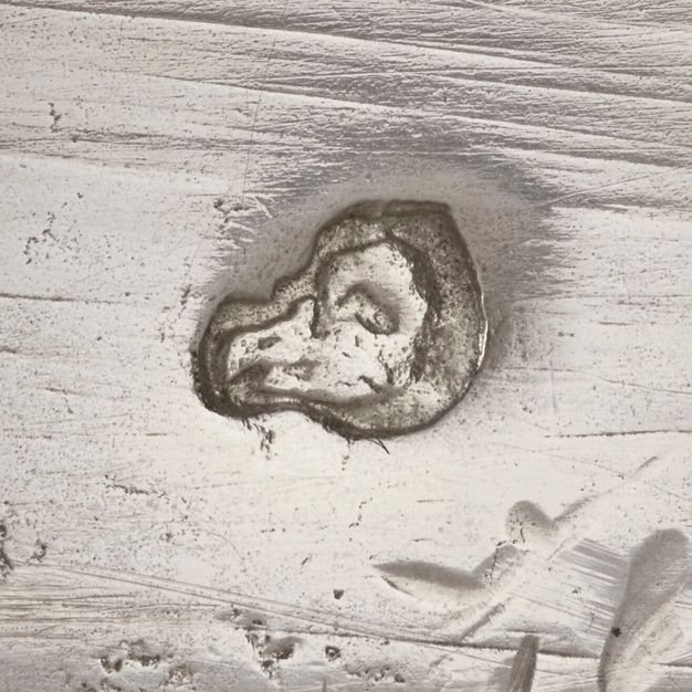 Close-up of an animal head or skull stamped on the vessel.