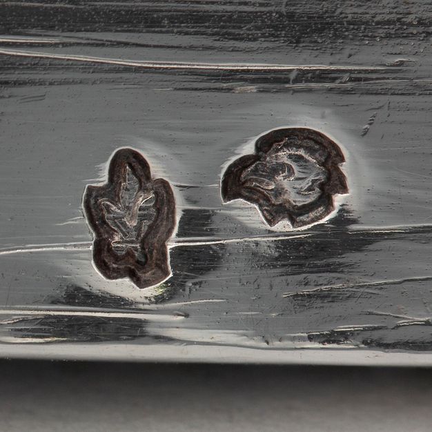 Close-up of a hen head and laurel leaves and stem stamped on the lid.