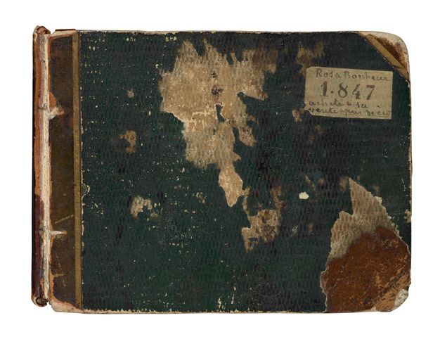 A dark-green textured sketchbook cover, scuffed and worn to reflect age and use, with loose binding. A yellowed white sticker is affixed to the upper right corner.