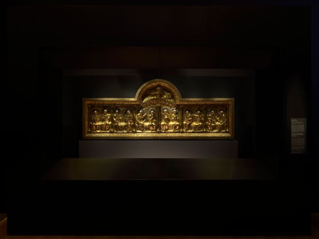 In a case in a dark gallery, a lighted, luminous, rectangular domed golden panel from a main altar shows the Pentecost, with twelve haloed apostles shown with tongues of flame above their heads.