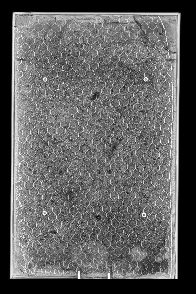 Honeycomb wire mesh in the back of a rectangular stone object, seen in black and white.