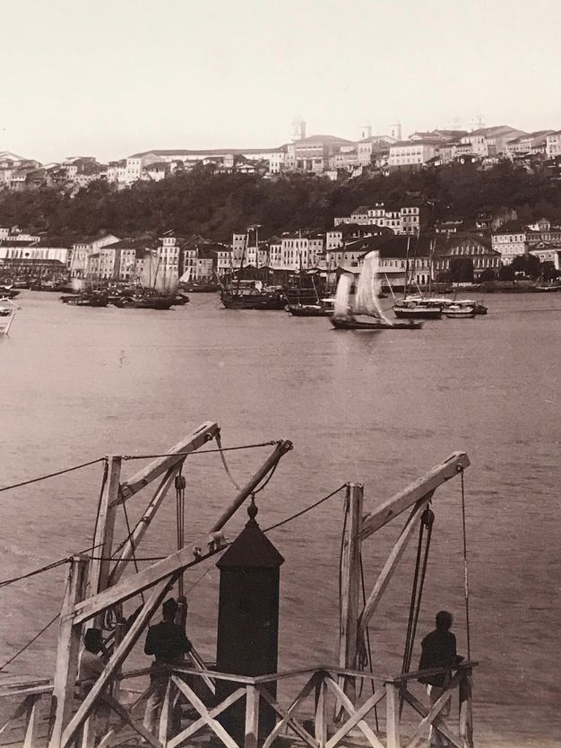 Details of this essay's figure one showing people on the dock, boats on the water, and coastal buildings.