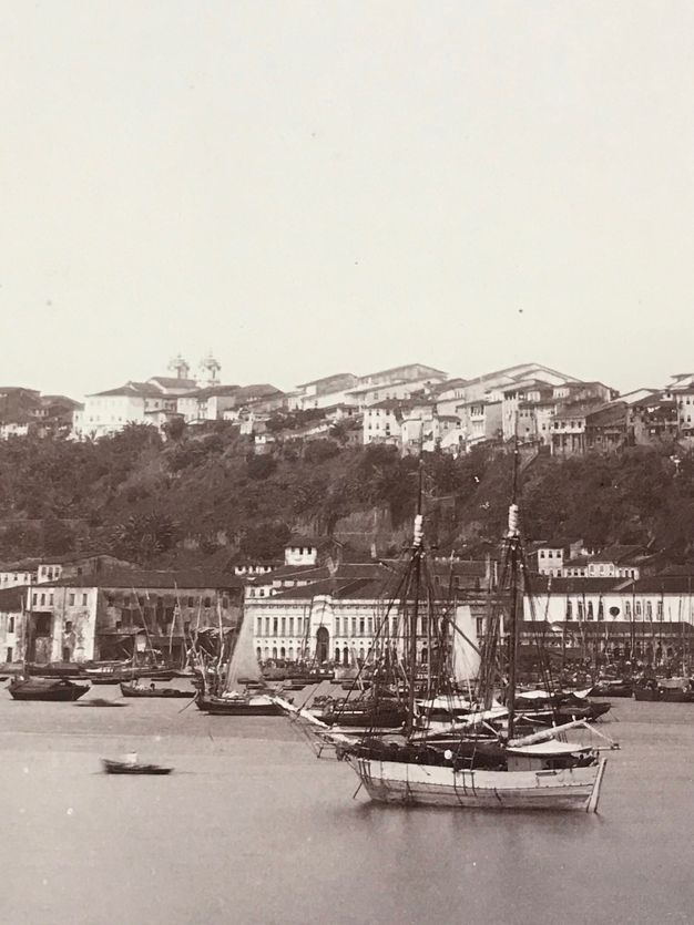 Details of this essay's figure one showing people on the dock, boats on the water, and coastal buildings.