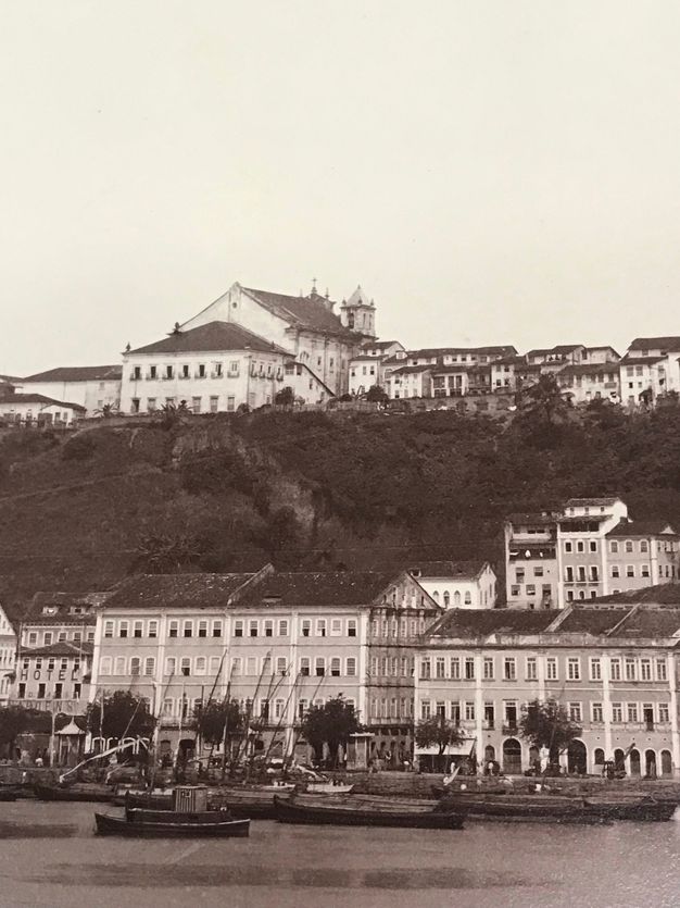 Details of this essay's figure one showing people on the dock, boats on the water, and coastal buildings.