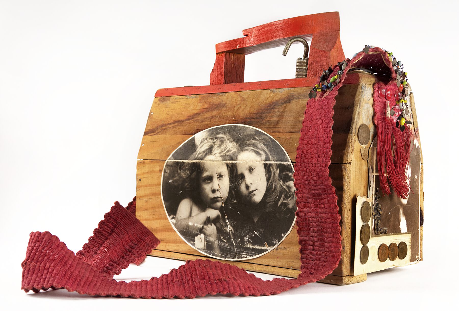 A wooden shoeshine box with a black and white photo pasted on the side with a red strap and red handle