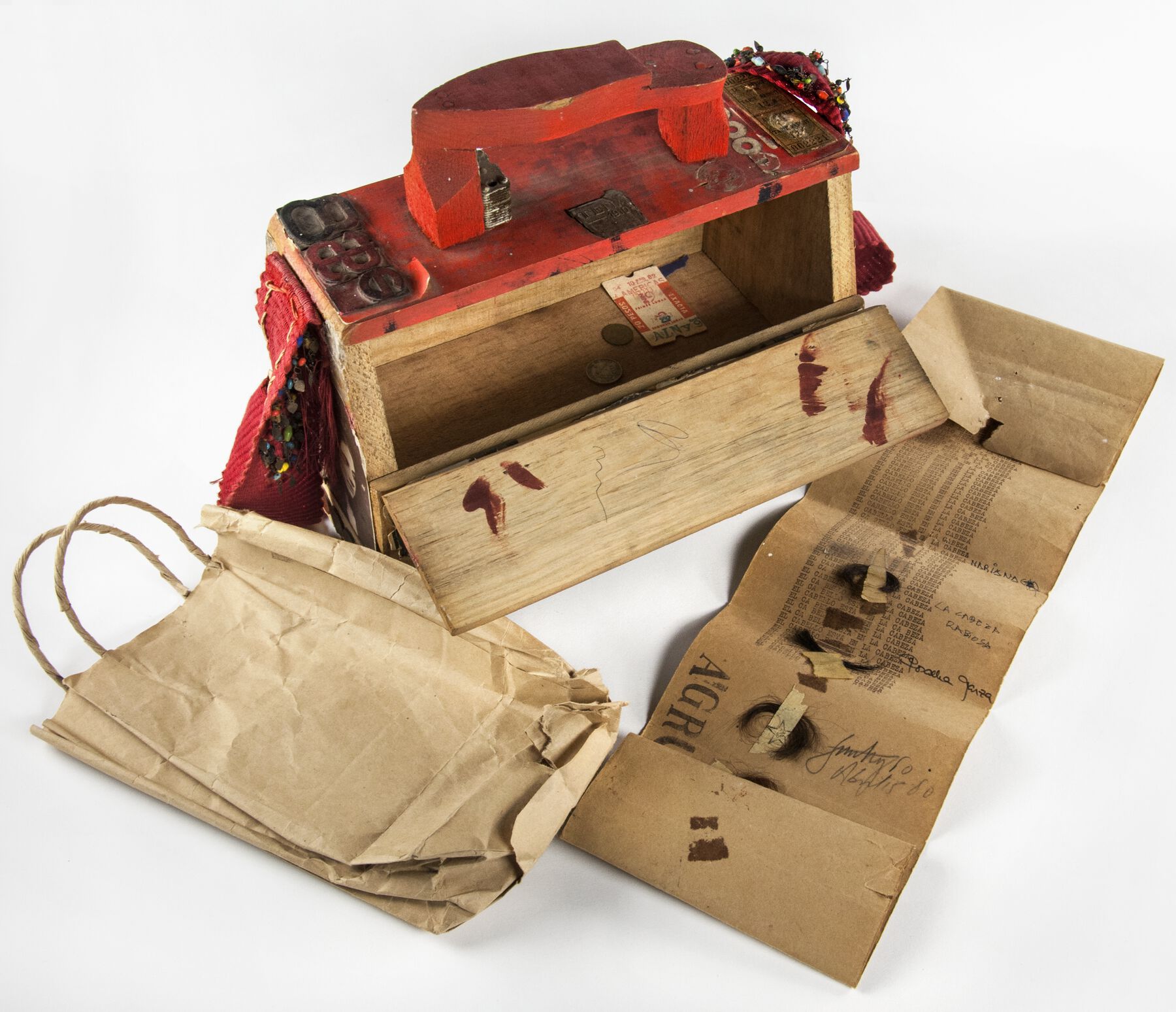 A open wooden shoeshine box with a brown paper bag laying on the left side and a manuscript spread out on the right side