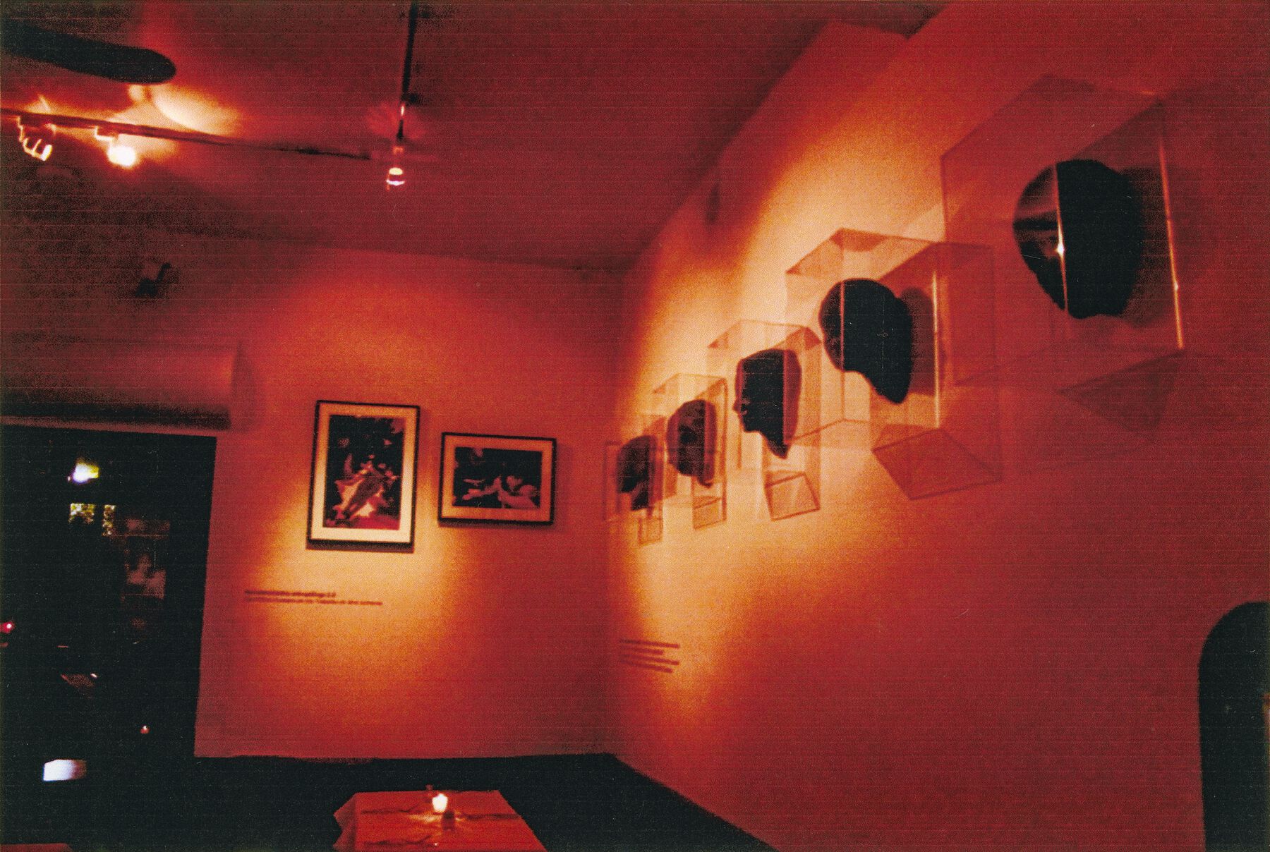 A dimly lighted gallery displaying 5 chocolate head sculptures with 2 art pieces in the distance