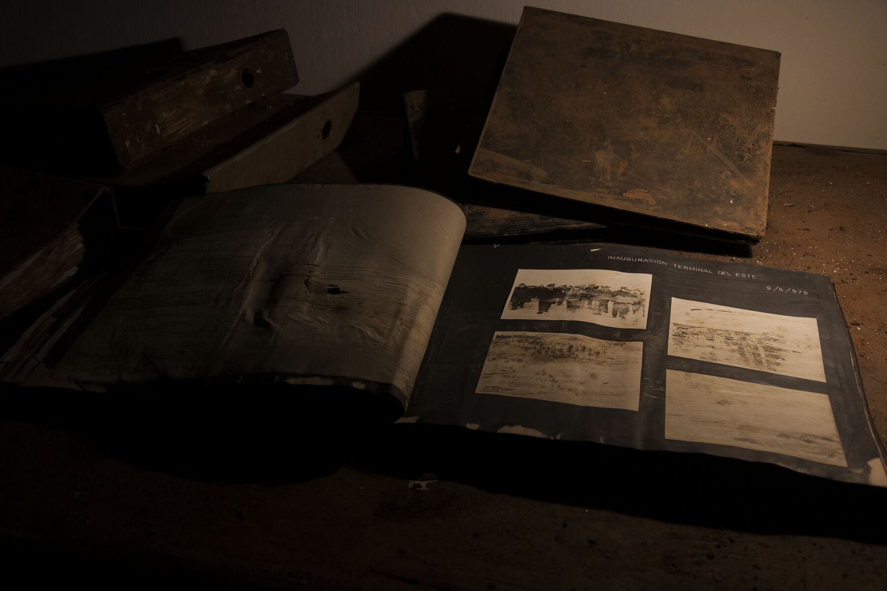 A close-up view of the lightly lit desk showcasing an open book with 4 deteriorating black and white photos