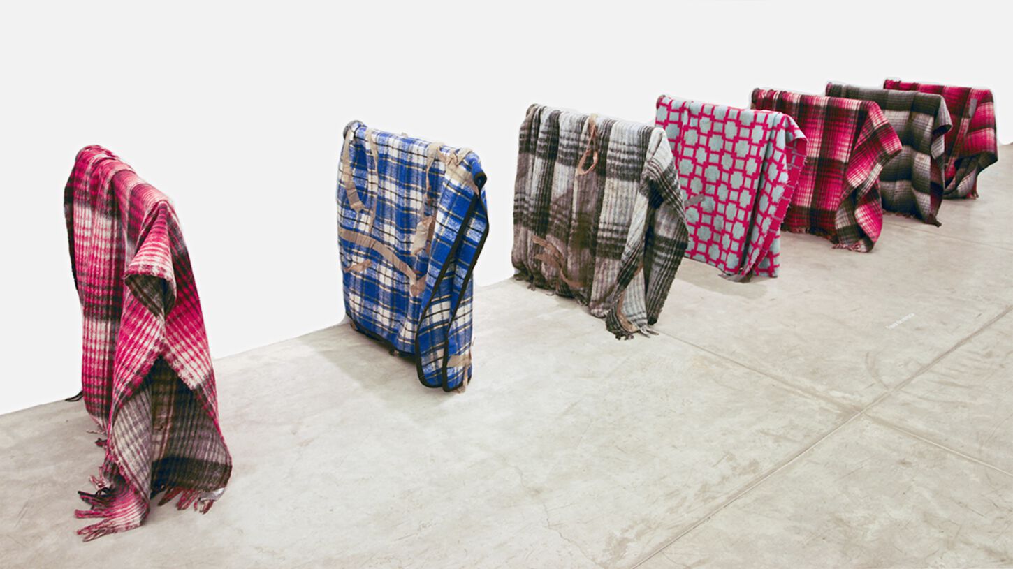 Three-quarter view of row of patterned red, blue, and plaid blankets standing upright in rectangular formations