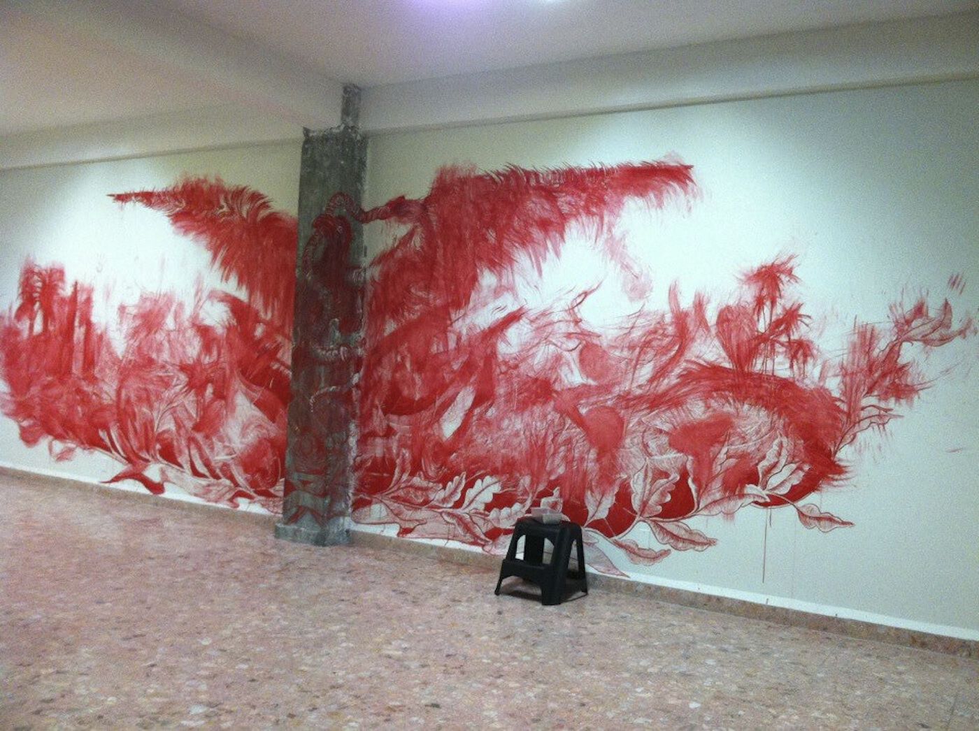Smeared red mural on wall with pink stains at edges; objects are indistinguishable except bordering leaves