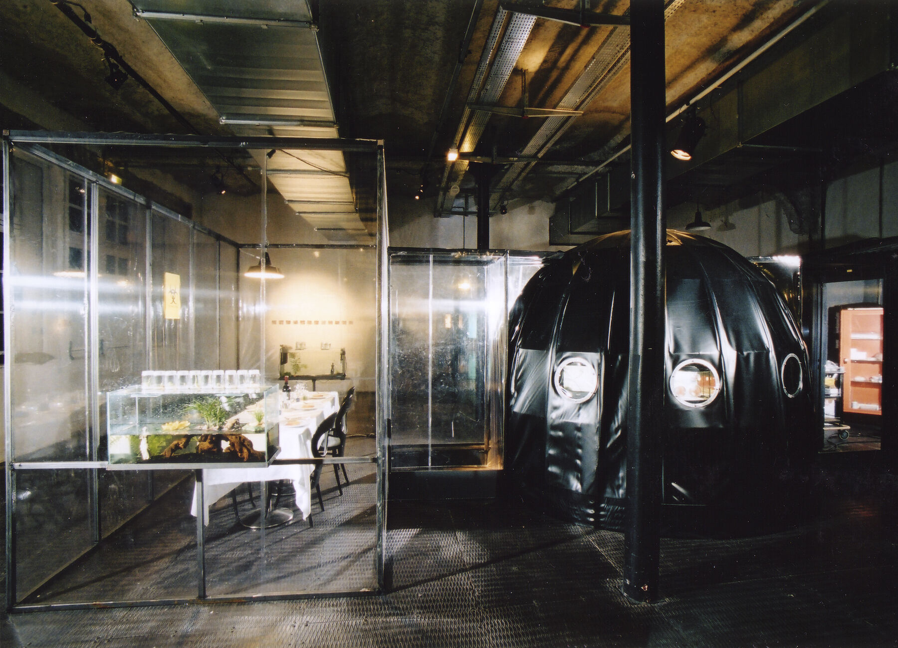A lab that contains tables with biological material with glass barriers protecting it with a black bubble dome sitting alone side.