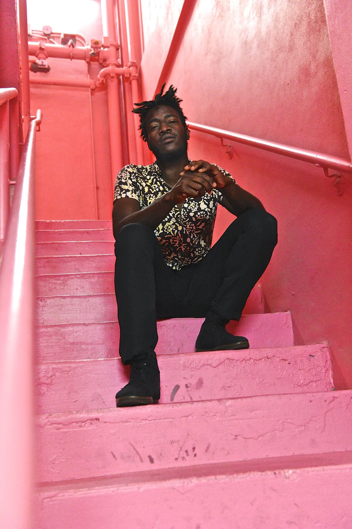 A low angle view of the artist sitting on a pink stairway