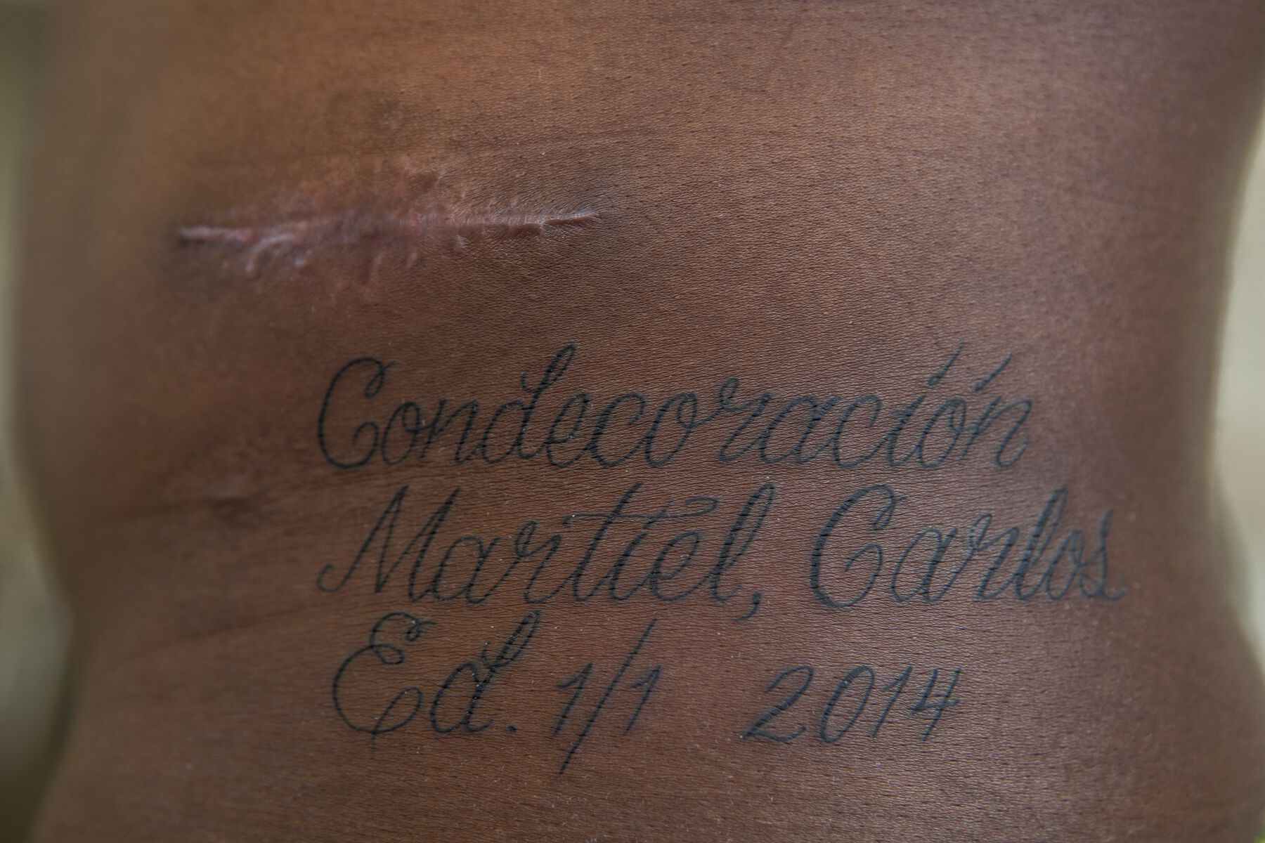 Back tattoo with calligraphy lettering that says Condecoracion Martiel Carlos Ed. 1/1 2014