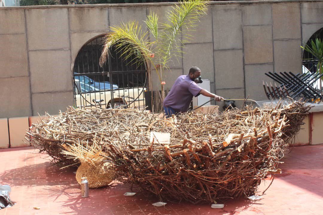 A man standing between two gigantic chicken nests while spraying them down with pesticides 