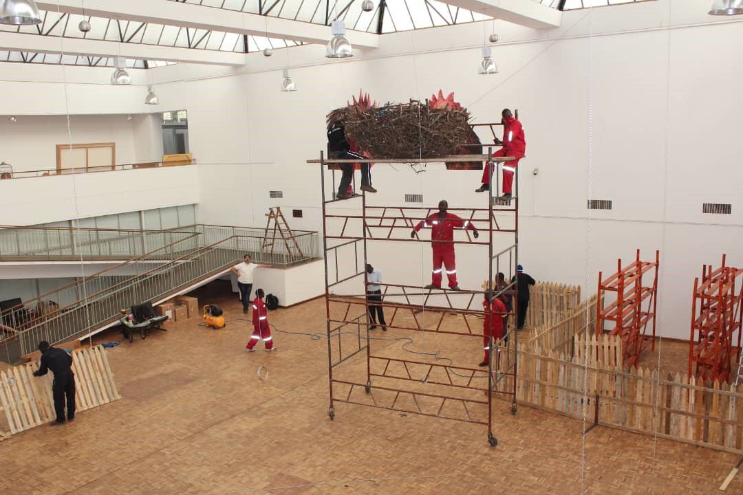 A elevated view of men working and standing on a scaffolding while adjusting one of the gigantic chicken nests