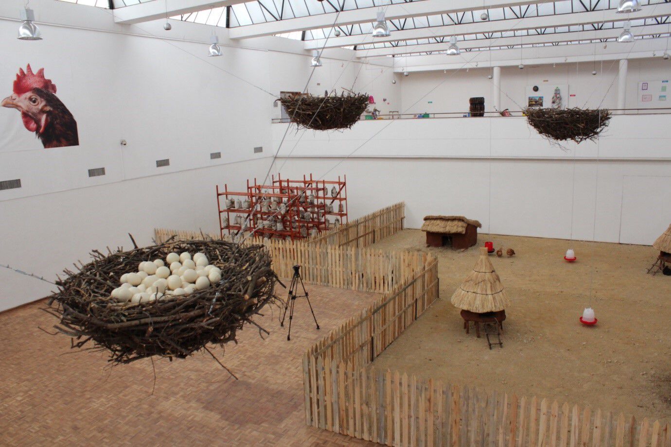 A elevated view of the installation that resemebles a farmhouse with the mushroom production on the left and three gigantic chicken nest hanging from wires