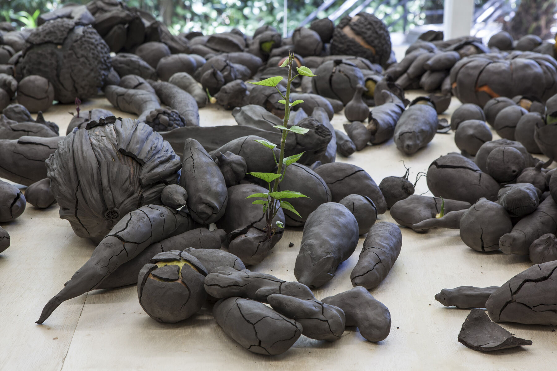 A table filled with fruits and vegetables with their clay molds including one that has a long sprout growing