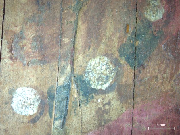 A close-up image of the lady's pearl and green-stone necklace. A 5 millimeter scale can be seen in the bottom right corner of the image. There are a few cracks on the surface of the painting. 