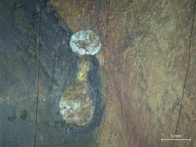 A close-up image of the lady's proper left earring. The earring features a pearl at the top and gold below. There are a few cracks on the surface of the painting.