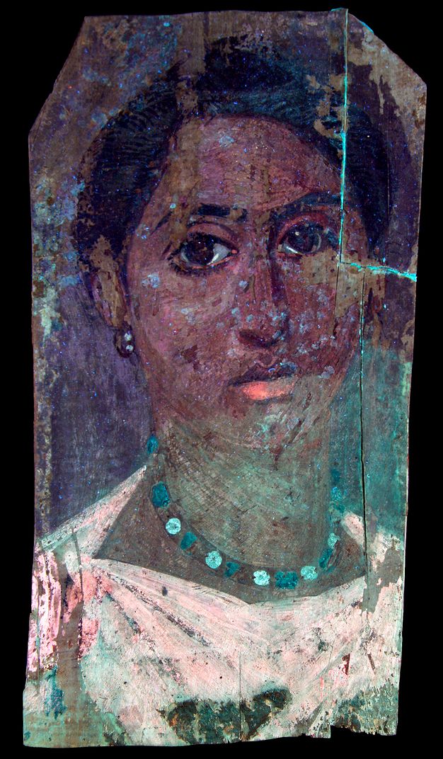 UVF image for figure 5.2. The woman's skin and hair appear darker and her pink garment appears lighter. The white beads of her necklace appear light blue, and the green beads appear a darker blue. Her bottom lip is colored with a brighter pink that also appears around her eyes and on the left side of her garment. There is a bright blue hue across the portrait, most notably on the right side of the woman's neck and around her chin. 