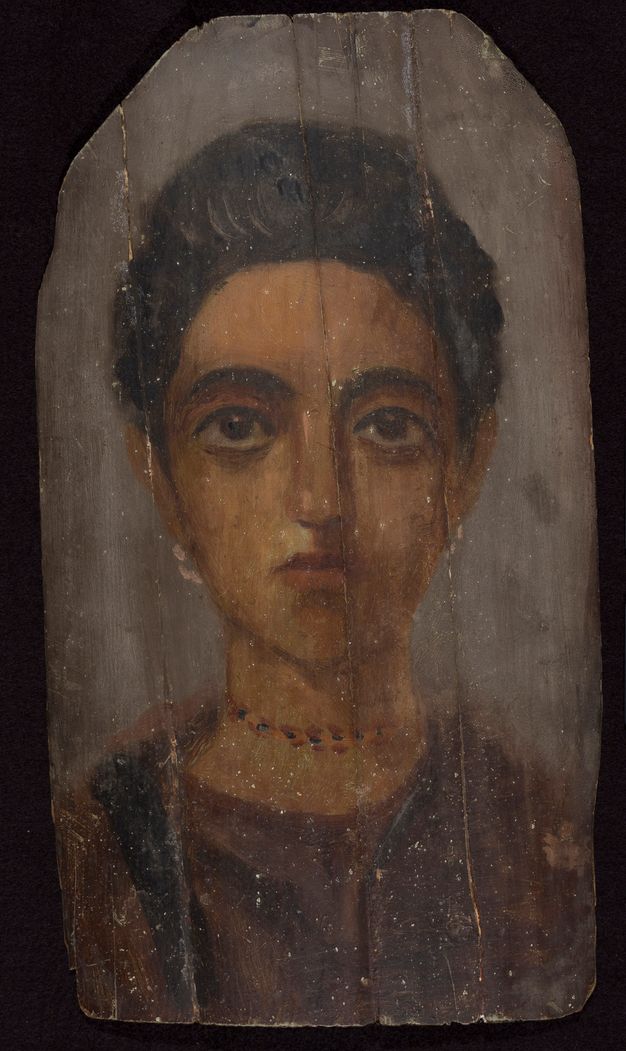 Portrait of a woman whose hair and eyes are dark brown. Her hair sits on top of her head, and her skin is tan in color. Her lips and eyelids have a pink tint. She wears a brown garment and is wearing white, hoop-shaped earrings and a multi-color necklace. The background of the portrait is gray in color. 