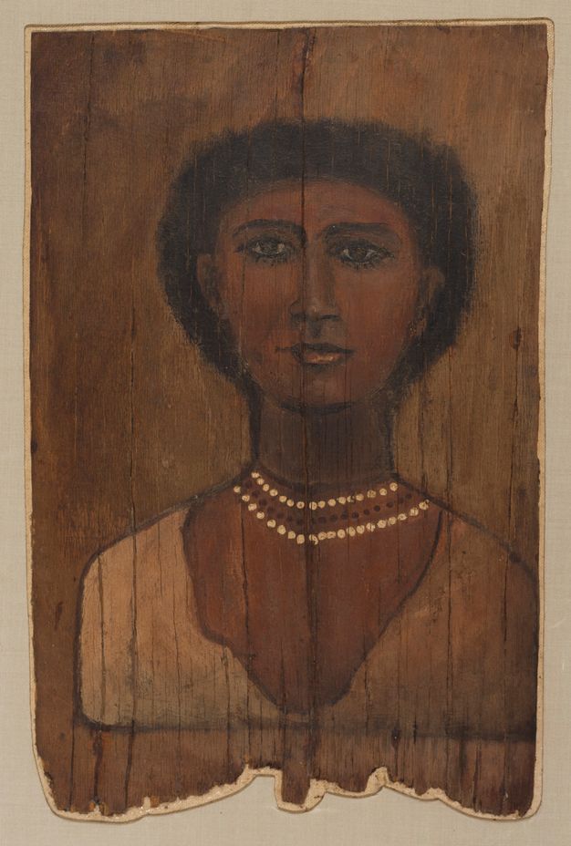 Portrait of a woman whose hair and eyes are dark brown. Her hair appears to be short, and her skin is brown. There is a reddish tint around her cheeks and chest. She is wearing a beaded black and white necklace and a white garment around her shoulders. The background of the portrait is brown.