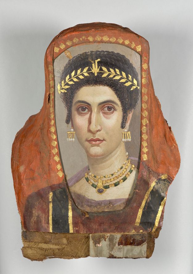 Portrait of a woman with dark brown textured hair decorated with a gold wreath. Her hair sits on top of her head. Her skin is fair and pale, with a pink tint around her eyes and on her lips. The woman's eyes are brown, and she is wearing gold and pearl earrings as well as a gold and green multi-layered necklace. The necklace has a dark pendant. The background of the portrait is white and orange. The outer background surrounding her shoulders and torso is orange. The inner background that frames her face and neck is white. There are small, gold, diamond shaped details that frame the white background. She is wearing a mauve garment that looks deeper red in comparison with the orange background. The garment has black and gold detailing on each side of her chest. 