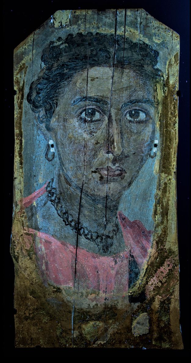 Ultraviolet-induced visible fluorescence image of the portrait in figure 8.15. The woman represented has dark hair and dark eyes. The image has a blue tint to it which makes the woman's skin appear darker than it is, and her garment bright pink. Her pearl earrings show black detailing and her necklace appears black. The background is primarily blue with brown streaks lining the portrait. 