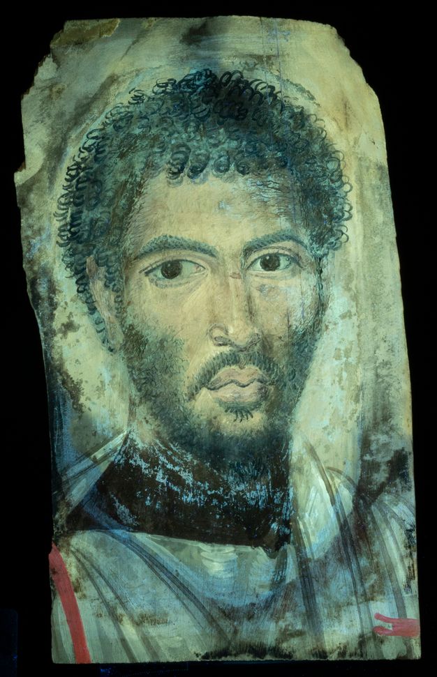 Ultraviolet-induced visible fluorescence image of a portrait. Much of the paint takes on a greenish-blue shade, but there is a vertical stripe of red across the garment of the man's proper right shoulder, and another glimpse of red disappearing across his proper left shoulder. There is an uneven bluish fluorescence most notable at his neck.