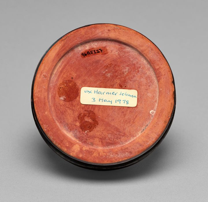 Underside of a ceramic vessel with a label written in black at the top that reads quote 96AE227 end quote. A white sticker at the center reads, in handwritten blue ink, quote ex Harmer Johnson, 3 May 1978 end quote.