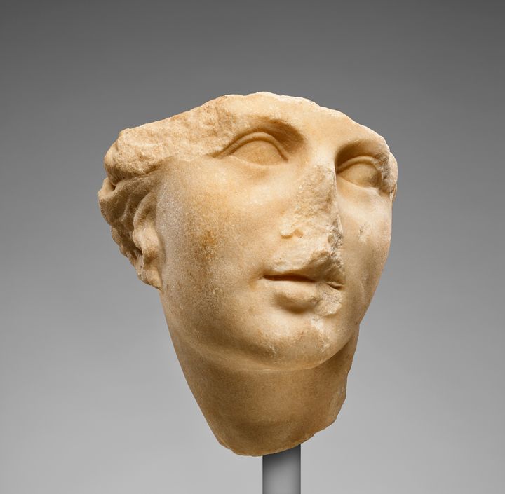 Fragment of a sculpted head showing a woman’s face from just above the eyebrows to the throat. Carved from cream-white marble, the face turns slightly to the right. The nose and part of the mouth have been lost.