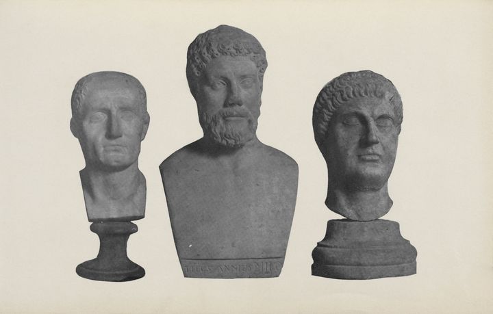 Back-and-white photograph showing three male busts in grayscale against a white background. Each bust shows a man’s head and neck, and the center also includes the chest.