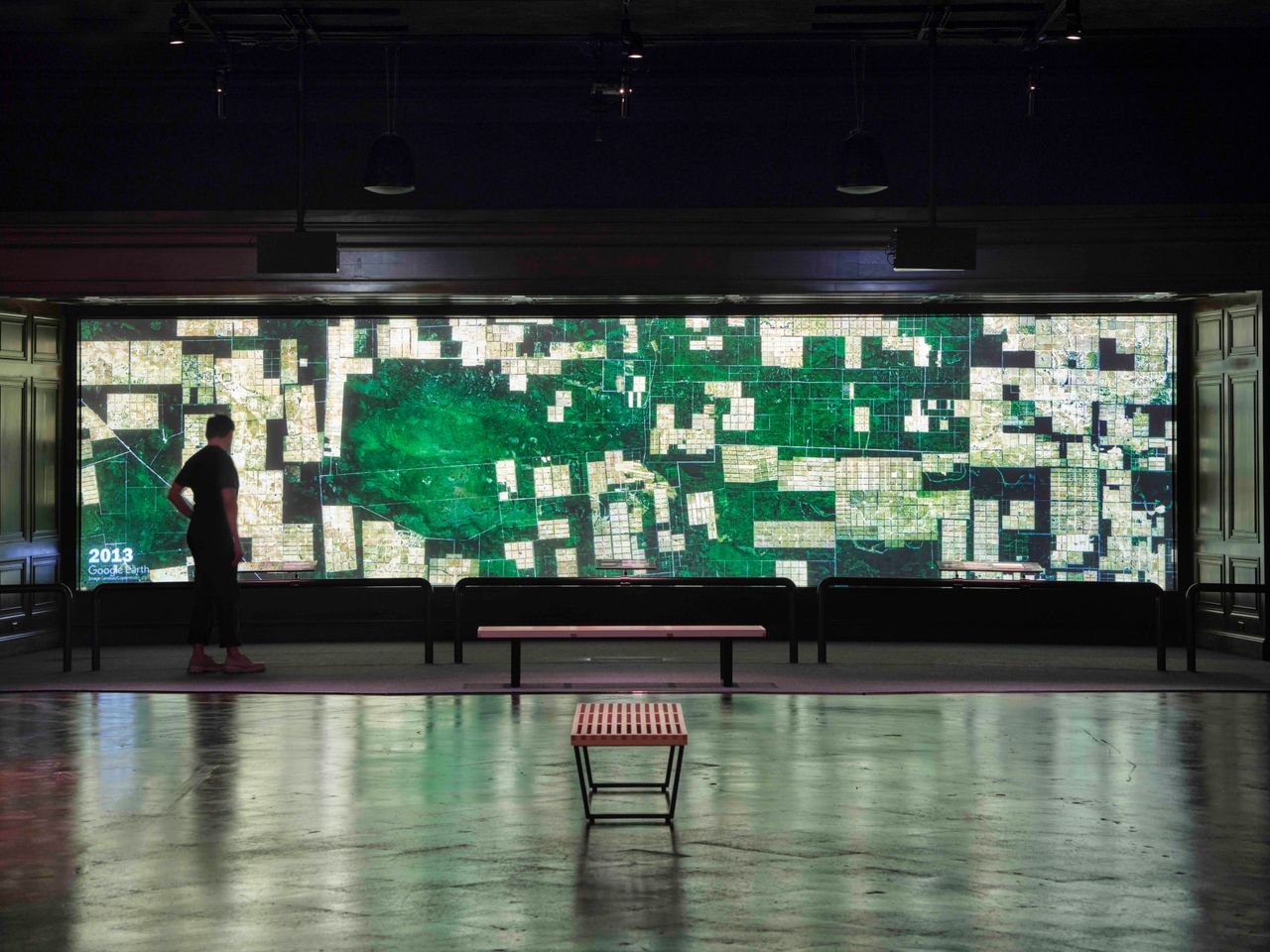 Person standing in front of a large screen displaying a map.