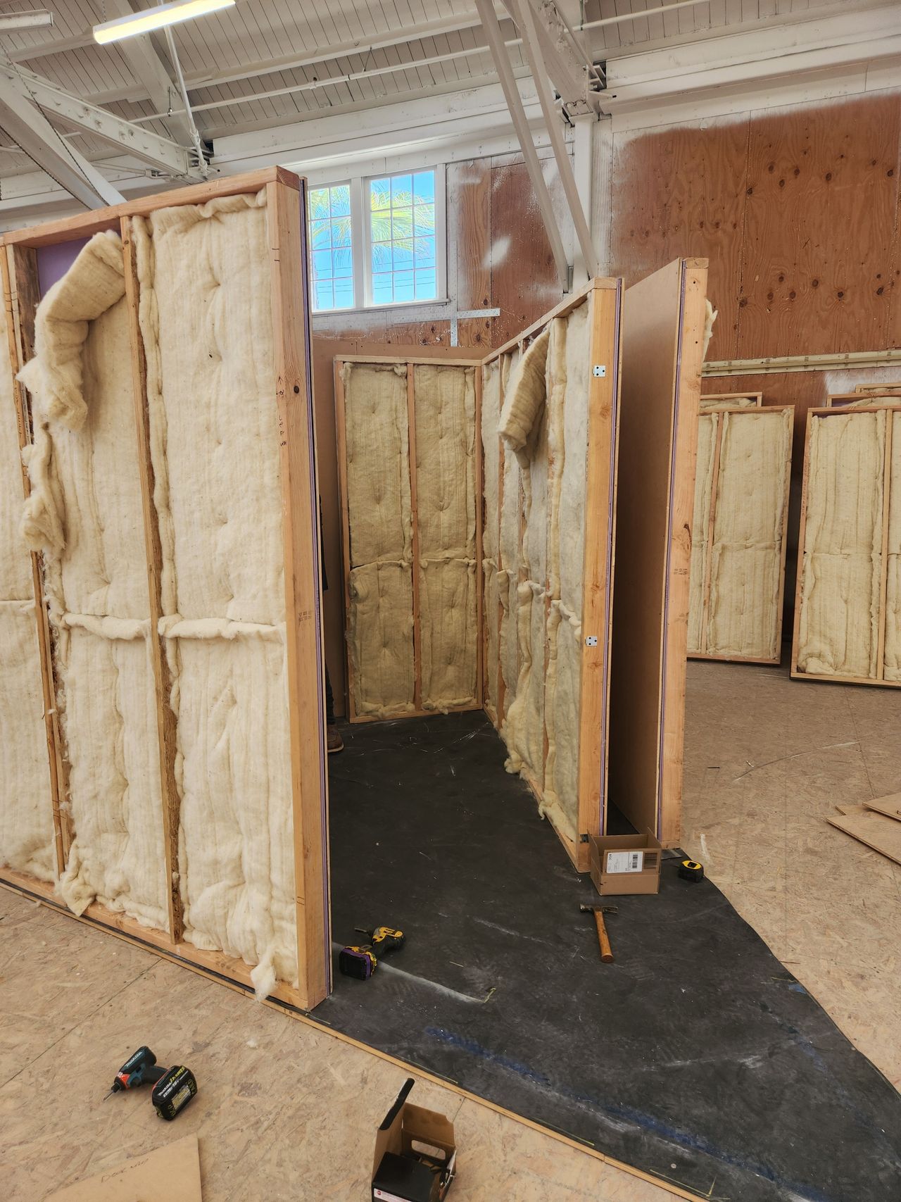 Large wooden walls showing interior filling in a studio setting with tools on the ground.