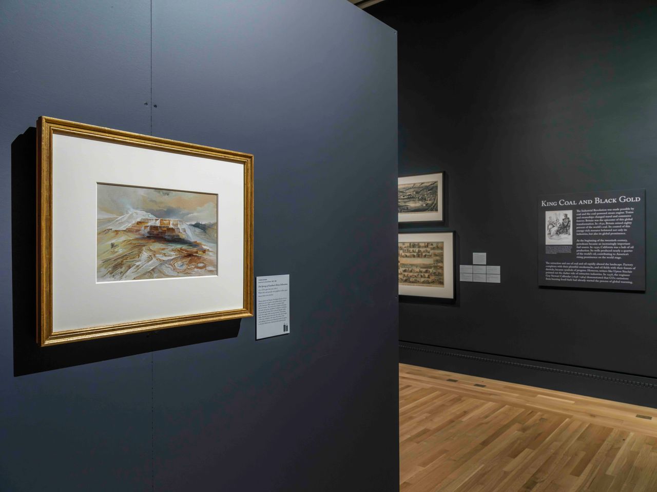 View of a museum gallery with a painting on a wall. The wall has visible screws and a seamline going down its middle.