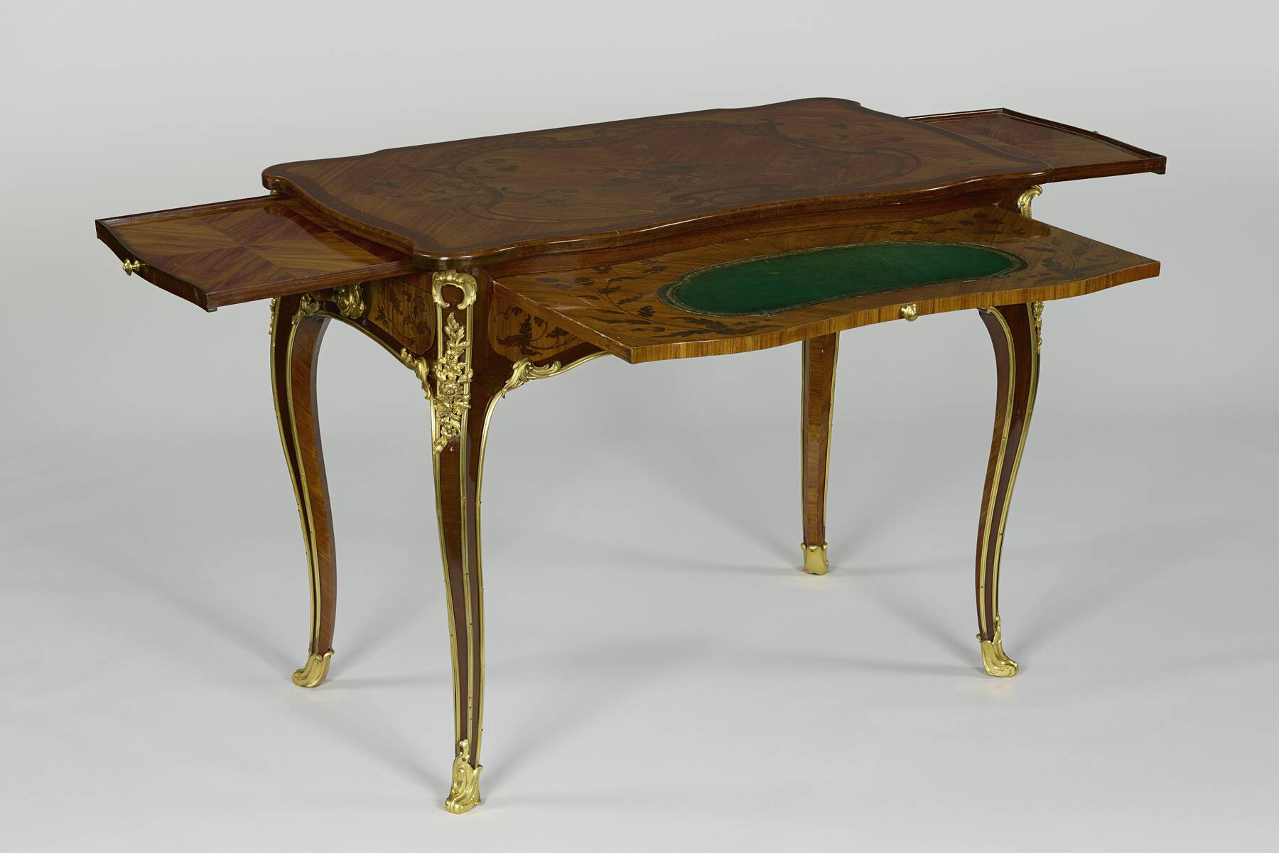 three-quarter view of the table with the slides pulled out, two smaller slides decorated with parquetry on the sides and a larger slide decorated with marquetry and green leather on the front