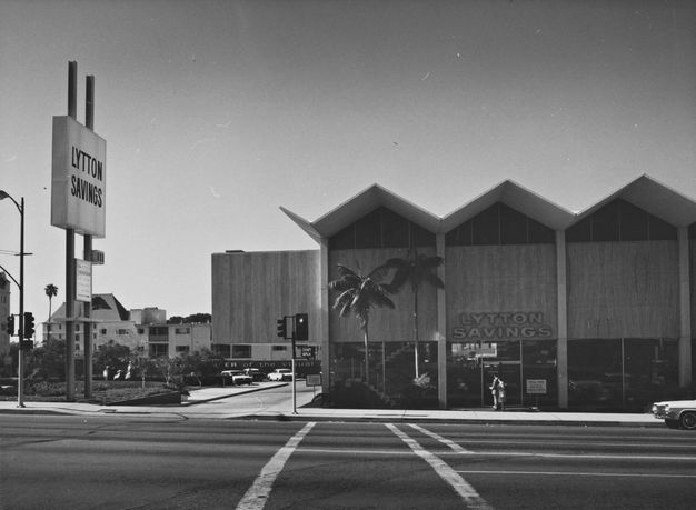 A black-and-white photo featuring a bank building shown from across the street.