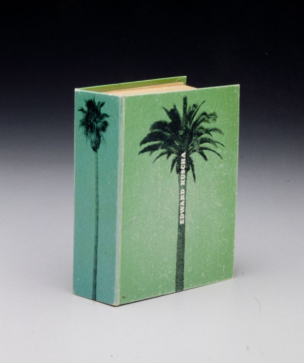 A bright green cover of a very small book. A single silhouette of a palm tree, isolated from its background, is printed on the cover with white lettering spelling “EDWARD RUSCHA” along the trunk.