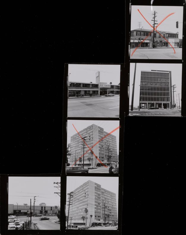 A contact sheet of six black-and-white photos showing multi-story buildings arranged in a partial grid, surrounded by black. The middle and top right photos have red “x” marks.