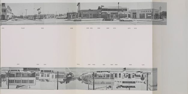 A book propped upright and unfolded in an accordion fold shows two long horizontal strips of black-and-white photos at top and bottom.