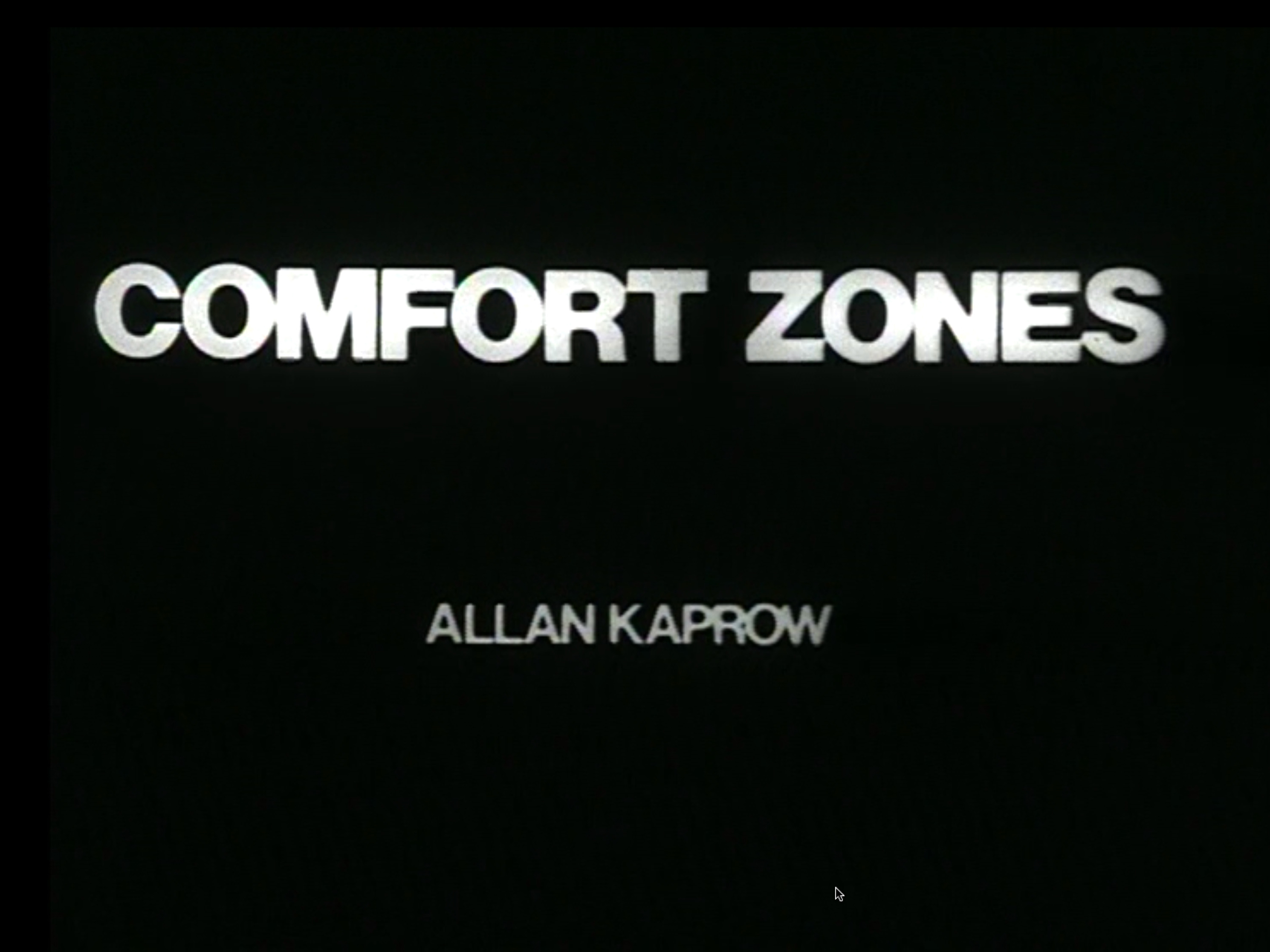 Black and white film opening with male voiceover followed by title card “Comfort Zones Alan Kaprow” in white on black background. Film alternates between title cards with three to five short sentences read aloud by male voiceover and video of one or two people performing the actions from the previous title card. Shots are stable and either close-ups focusing on hands or faces, or wide shots of chest-up or full-body figures. Close-ups often capture movement or speech. Figures or hands are typically at the center of the frame, with no other points of visual interest. First half of video takes place indoors, and the second, outdoors. Four by three aspect ratio. 