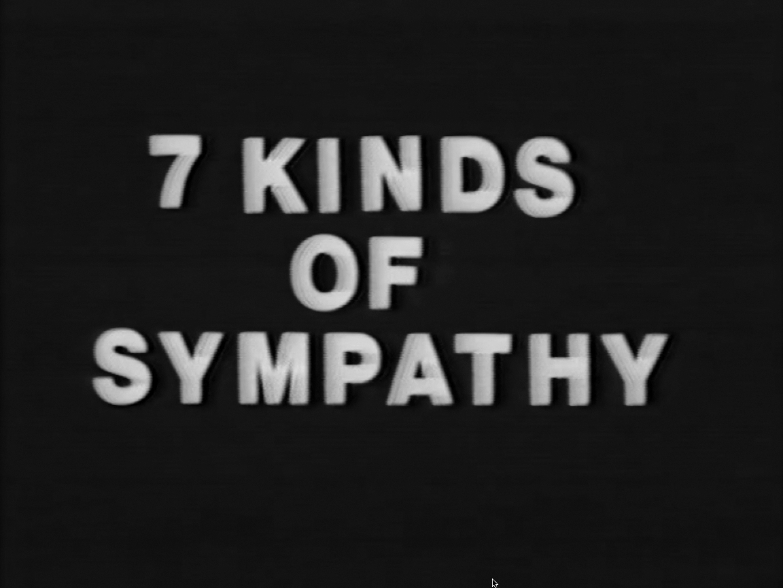 A color film opening with a male voiceover and a blank white screen followed by title card that reads, 7 Kinds of Sympathy in white on blue background.&nbsp;The film cycles through the following. 1, a male voiceover accompanied by blank white background. 2, a color video of one or two people, either together or separate, performing actions from the voiceover. And 3, a title card with the word later in white on blue background.&nbsp;Shots are stable and either close-ups focusing on hands or faces or wide shots of chest-up or full-body figures. Close-ups often capture movement or speech. Figures or hands are typically at the center of the frame, with no other points of visual interest. Background of scenes is either solid orange or solid red. Both figures wear maroon plain clothes. Four by three aspect ratio.
