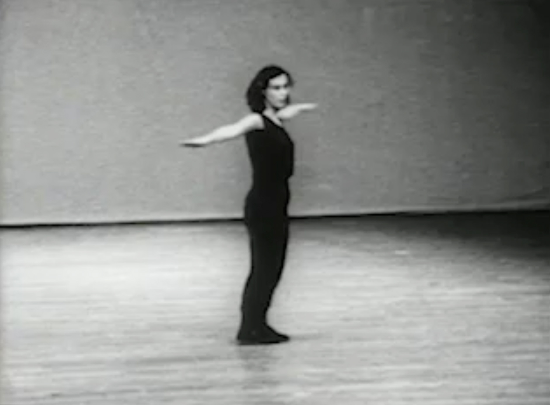 Silent black-and-white video of a woman (Yvonne Rainer) dancing alone in a studio, wearing all black. Occasionally the camera zooms in on a segment of her body or on a particular body part, such as the feet.