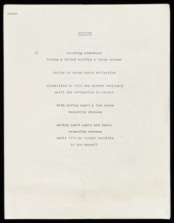 White page with black typewritten text in English, center-justified, attached to other pages with a staple in upper-left corner. Some pages are notated in pencil.
