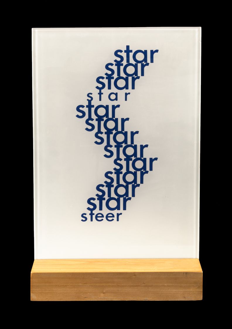 Upright sandblasted glass rectangle with the word, star repeated several times in blue text of varying thickness to create a zig-zag shape at center that terminates with the word, steer printed once.