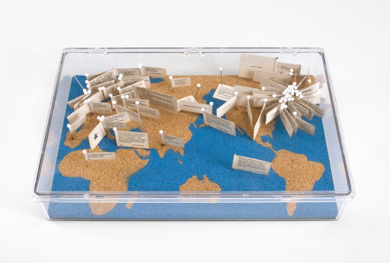 A map presented within a clear box. Flags with unidentifiable markings or text on them are peppered throughout the map, centered around New York City but extending worldwide.